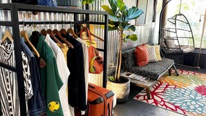 Ein Zimmer mit einer Kleiderstange, einem Sofa, einem Hängesessel und einem Blumentopf.
