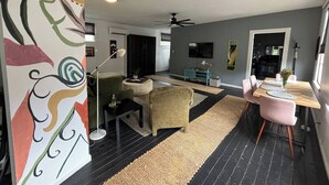 A modern living room with a sofa, a coffee table, and a dining area with a table and chairs. - Chic Algiers Point loft with king bed. Walk to ferry, minutes to French Quarter & jazz. (New Orleans)