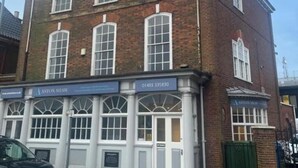 A two-story brick building with large windows and a sign for 'ASTON SHAW'. - Church View Apartment - Nelson's Retreat (Great Yarmouth)