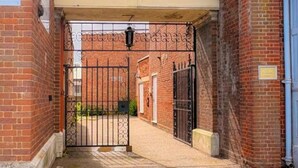 Un vicolo stretto con un cancello, muri in mattoni e una porta blu sulla destra.