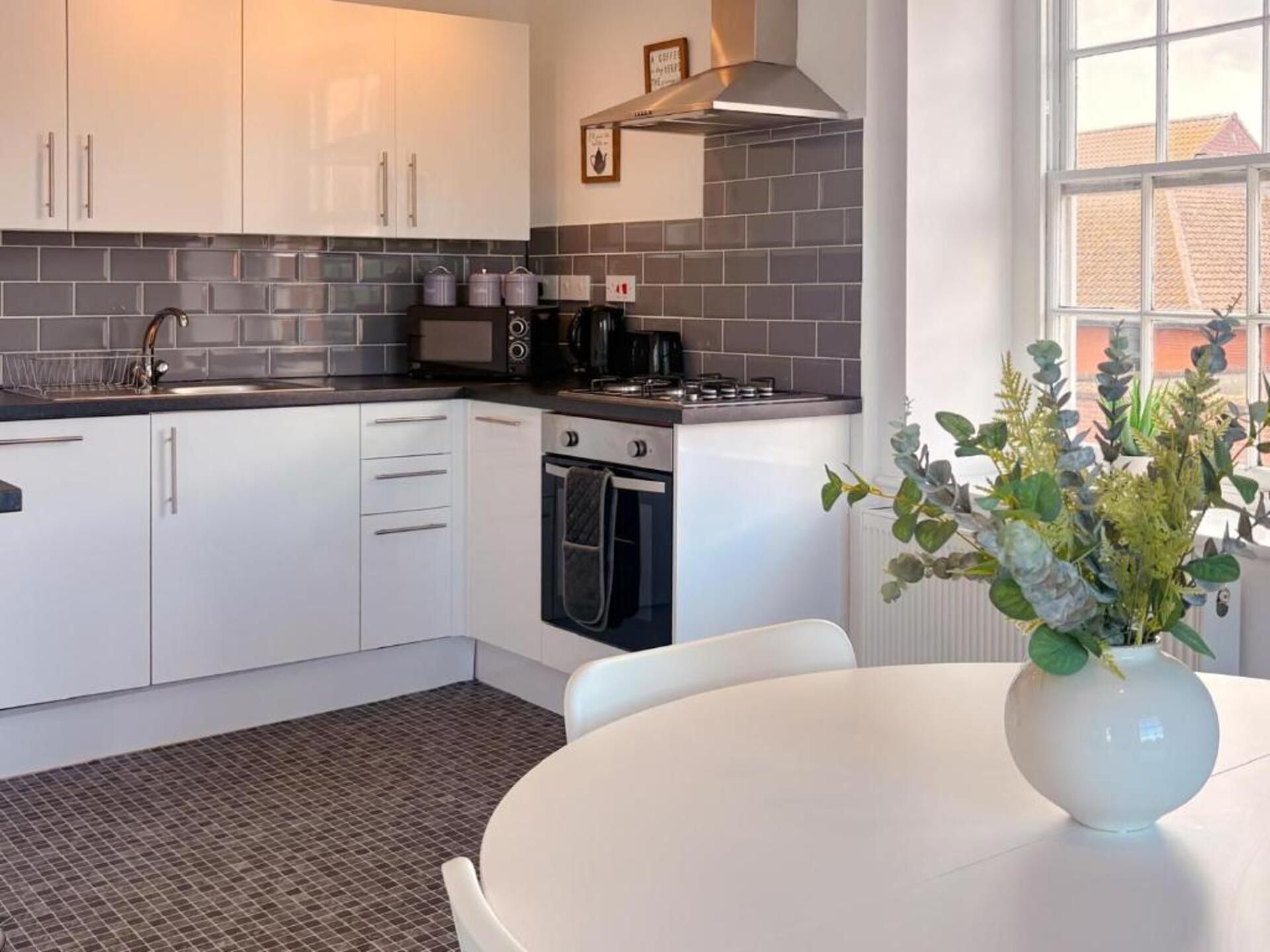 A modern kitchen with white cabinets, a gas stove, and a coffee machine.