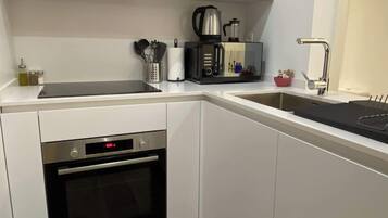 Eine moderne Küche mit weißen Schränken, einem Einbauofen, einer Kaffeemaschine und einem Wasserkocher.