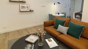 A modern living room with a brown sofa, a coffee table, and a small round table with a lamp.