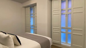 A bedroom with a bed, a window with frosted glass, and a door.