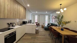 Et moderne køkken med en central ø, et spiseområde med et træbord og stole, og en opholdsstue med en sofa og et sofabord.