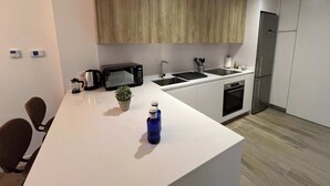 Una cucina moderna con microonde, lavello e fornello. Sul piano di lavoro c'è una piccola pianta e una bottiglia d'acqua blu.