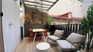 A patio with a table and chairs, a round concrete stool, and a potted plant.