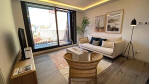 A modern living room with a sofa, a coffee table, and a TV on a stand. - w* | Stylish 2BR w/ Sunny Terrace in Chueca (Madrid)
