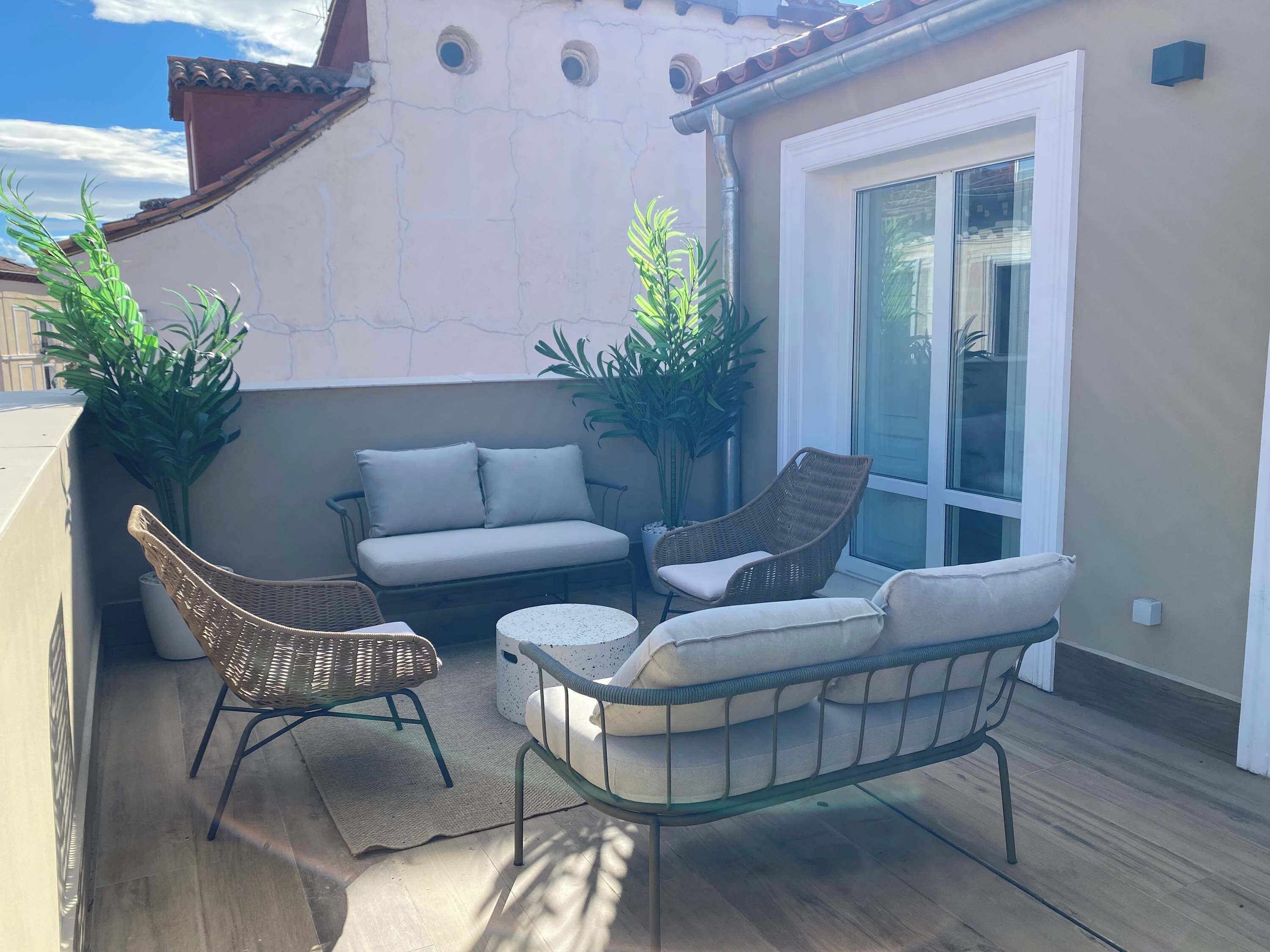 Eine Terrasse mit Korbmöbeln, einer Couch und Blumentöpfen.