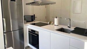 Moderni keittiö, jossa on ruostumattomasta teräksestä valmistetut kodinkoneet, mikroaaltouuni, pesuallas ja astianpesukone.