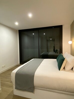 A modern bedroom with a large bed, a sliding glass door, and a small bedside table. - w* | Modern 2BR with Terrace in Chueca (Madrid)