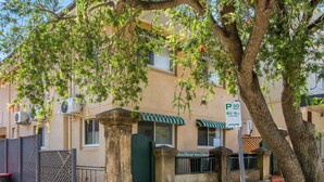 A building with a green awning, a tree, and a parking sign. - Chic 1-bed Retreat Near Shops & Beach (Sydney)