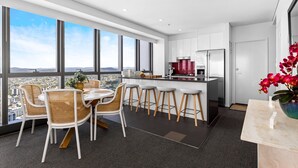 A modern kitchen with a large island, white cabinetry, and a view of the city.