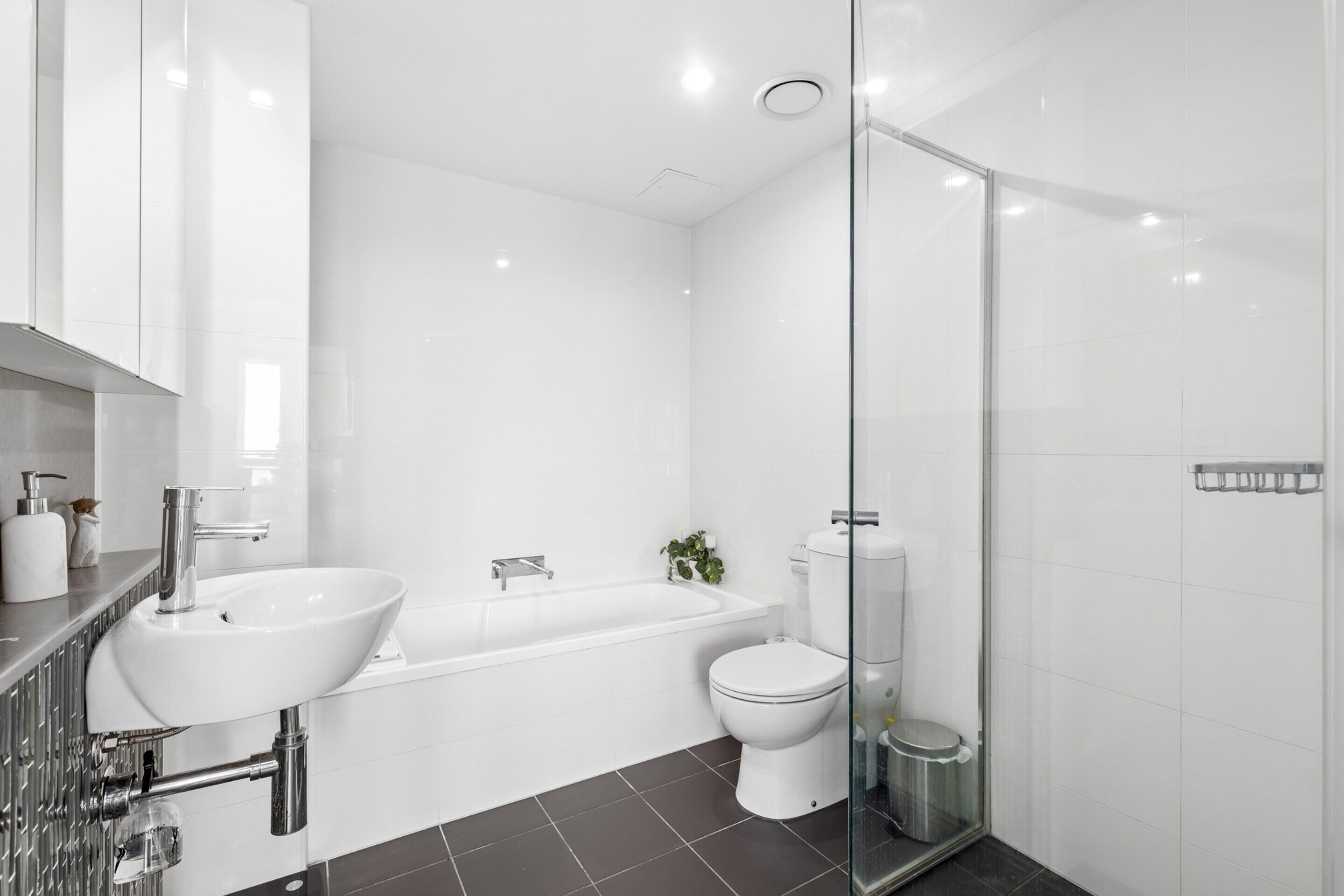 Une salle de bain moderne avec un lavabo, une baignoire et des toilettes, le tout de couleur blanche.