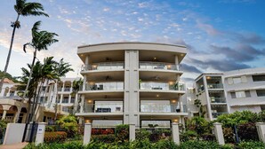 A multi-story hotel with balconies, palm trees, and a clear sky. - Beachfront 3-bed With Pool & Stunning Ocean Views (Cairns)