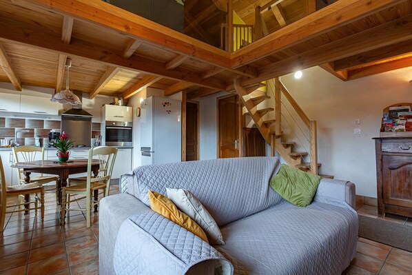 Un salon confortable avec un canapé, une table à manger et des chaises. Un escalier mène à l’étage supérieur.