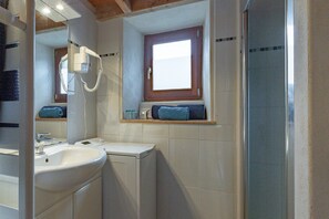 Une salle de bain équipée d’un lavabo, d’un miroir, d’une fenêtre et d’une douche.