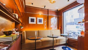 A cozy interior with a sofa and two small tables, a window with a view of the street, and a wooden wall with framed pictures. - Confidential Room 4, a Stone's Throw From the Louvre (Paris)