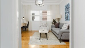 A modern living room with a grey sofa, a white coffee table, a lamp, and a painting on the wall. - Coastal Living Just Metres From Coogee Beach (Sydney)