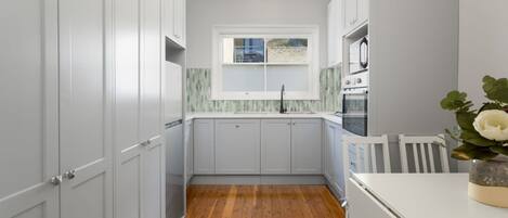 A kitchen with white cabinets, a wooden floor, and a window with a view.