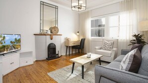 A modern living room with a fireplace, a television, a desk, and a comfortable seating area. - Coastal Living Just Metres From Coogee Beach (Sydney)