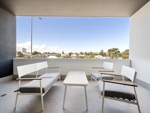 A balcony with two white chairs and a small table, overlooking a residential area with houses and trees. - Modern 1-bed Apartment With Views in Fremantle (Perth)