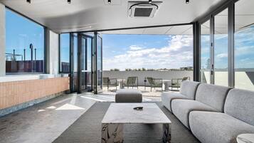A modern outdoor seating area with a sofa, chairs, and a marble table, overlooking a cityscape.