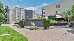 A modern building with a paved entrance, a logo on the wall, and a nearby restaurant. - Sleek 2-bed Apartment in Vibrant Kingston (Canberra)