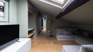 Un salon moderne doté d’un téléviseur à écran plat, d’un canapé et d’une lucarne au plafond.
