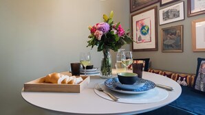 Une table à manger avec un panier à pain, un vase de fleurs, des verres à vin et une assiette avec une tasse.