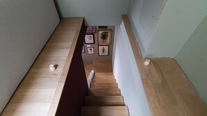Un escalier en bois, avec un mur à texture et des œuvres d’art encadrées accrochées au mur.