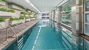A long indoor swimming pool with a tiled floor, metal handrails, and a ceiling with recessed lighting. - Eclectic 1-bed Apartment With Pool and Gym (Melbourne)