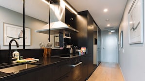 Cozinha moderna com armários escuros, eletrodomésticos de aço inoxidável e uma bancada comprida.
