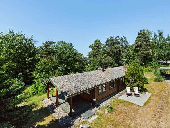 A cabin with a covered porch, a chimney, and a small deck with chairs.
