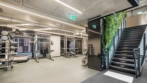 A gym with weightlifting equipment, a staircase, and a green wall. - Executive 2-bed Apartment With Views, Gym and Spa (Melbourne)
