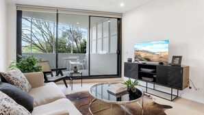 Ein modernes Wohnzimmer mit Sofa, Couchtisch und Fernseher.