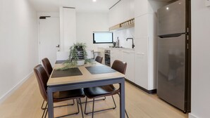 Eine moderne Küche mit Esstisch, Stühlen, einem Kühlschrank und einem Fernseher.