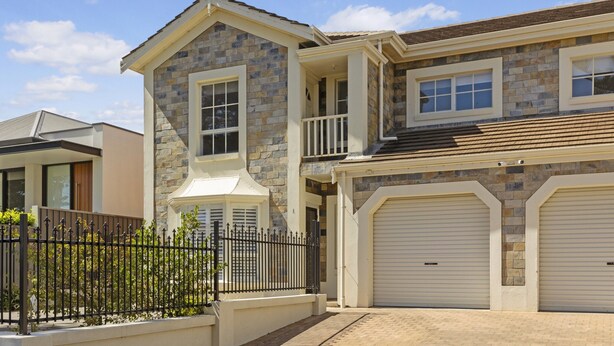 A two-story house with a stone facade, a balcony, and a garage with two doors. - Coastal 3-bed House With BBQ and Private Courtyard (Adelaide)