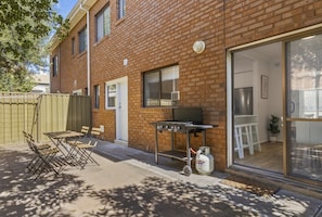 A brick building with a sliding glass door leading to a kitchen area. - Coastal 3-bed House With BBQ and Private Courtyard (Adelaide)