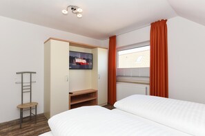 A bedroom with two beds, a wardrobe, a desk, and a window with curtains. - Ferienwohnung Balkon zur Sonnenseite in Bensersiel (Esens)