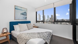 Une chambre moderne avec un grand lit, une vue sur la ville et un tableau encadré au mur.