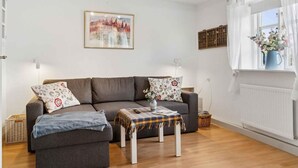 A living room with a grey sofa, two matching armchairs, a coffee table with a plaid tablecloth, and a framed picture on the wall. - 4 Star Holiday Home in Norre Alslev (Norre Alslev)
