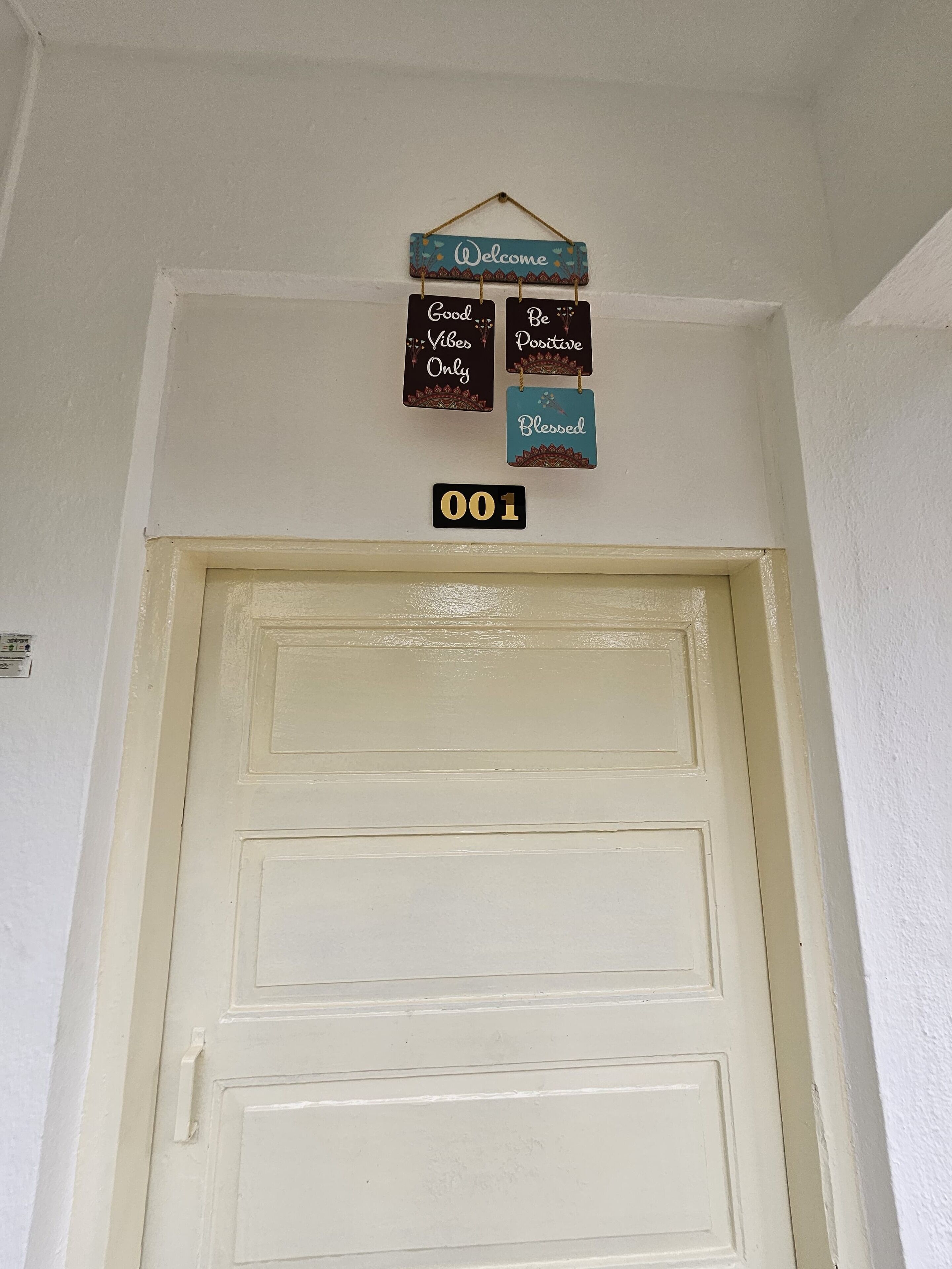 Μια λευκή πόρτα με μια επιγραφή από πάνω που γράφει «Καλώς ήρθατε» και «Μόνο θετική ενέργεια».