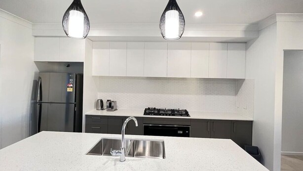 Una cocina moderna con una isla central, electrodomésticos de acero inoxidable e iluminación colgante.