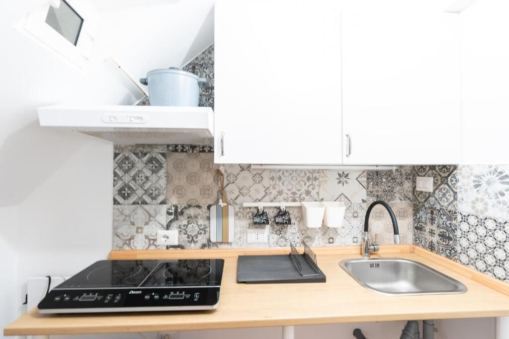 Een keuken met een zwart inductiekookveld, een spoelbak en een wit kastje erboven.