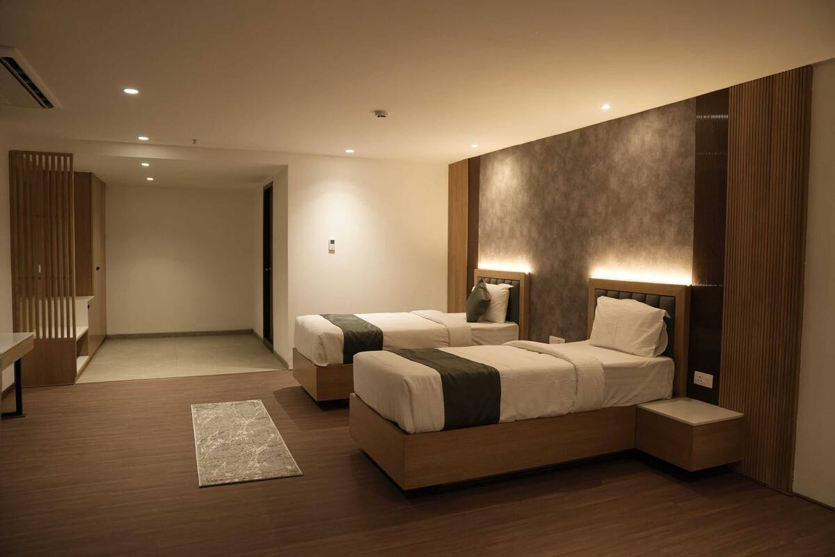 A modern hotel room with two beds, a desk, and a large mirror.