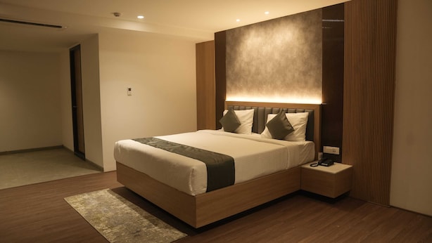 Une chambre d’hôtel moderne avec un grand lit, une table de chevet avec un téléphone et un luminaire fixé au mur.
