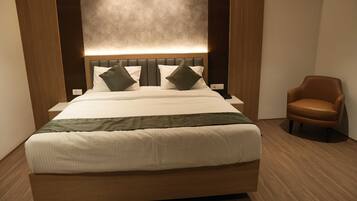 Una habitación de hotel moderna con una cama grande, un cabecero de madera y un sillón de cuero marrón.