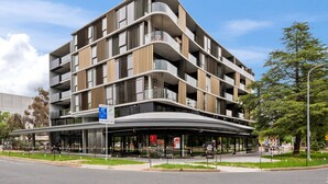 A multi-story building with a curved facade, balconies, and a covered entrance area. - Stylish Studio in Braddon With Communal Area (Canberra)
