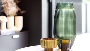 A modern interior with a round wooden table, a green vase, and a small bowl. - Stylish Studio in Braddon With Communal Area (Canberra)